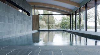 Minimally framed glass walls with heated glass to residential swimming pool spa